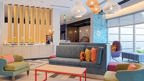 A modern lobby with a sofa, armchairs, a coffee station, and a reception desk. - Tru By Hilton Atlanta Airport College Park (College Park)