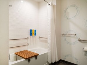 Ein Badezimmer mit einer weißen Badewanne, einem Holzbodenregal und einer Duschkabine mit Vorhang.