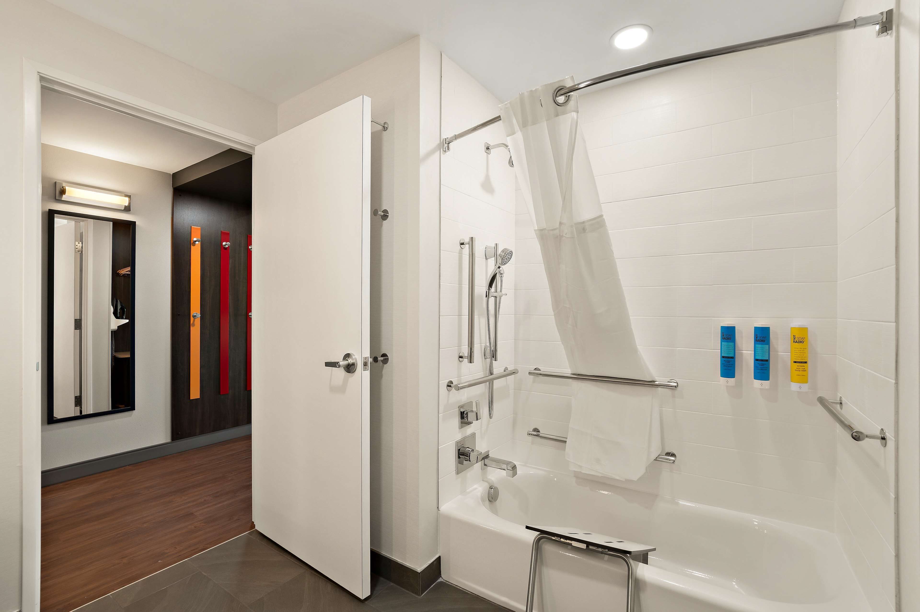 A modern bathroom with a walk-in shower, a bathtub, and a toilet. There are toiletries on the wall and a towel rack.