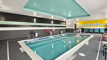 Une piscine intérieure avec des lignes de démarcation bien visibles, un sol carrelé et un plafond orné d’un motif géométrique.