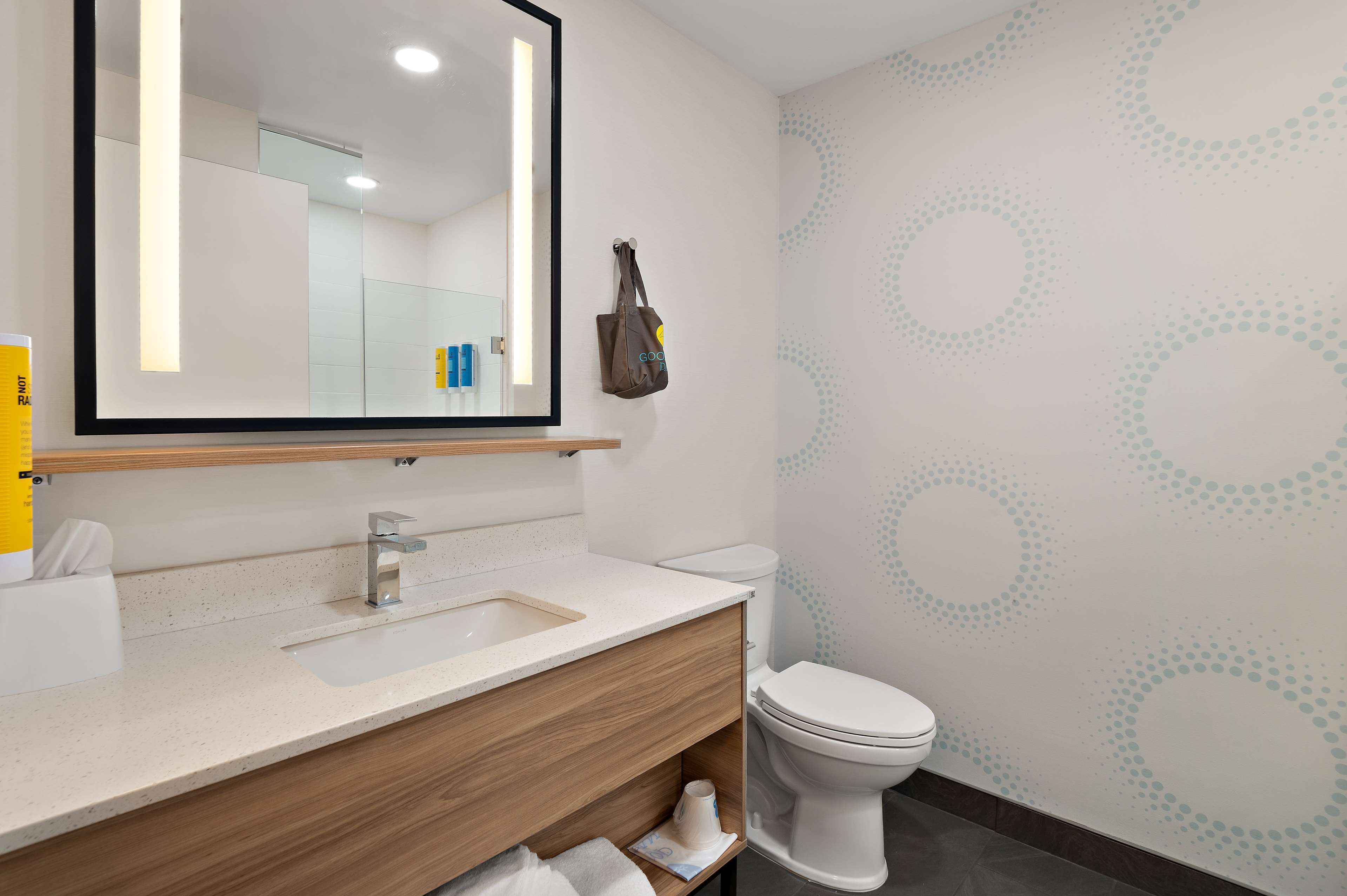 A modern bathroom with a large mirror, a sink, and a toilet.