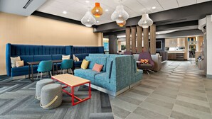 A modern lobby with a blue sofa, teal chairs, and a wooden table. - Tru By Hilton Santee (Santee)