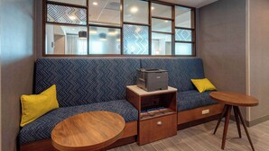 A modern seating area with a sofa, a small wooden table, and a printer on a side table. - Hampton Inn Marianna I-10 (Marianna)
