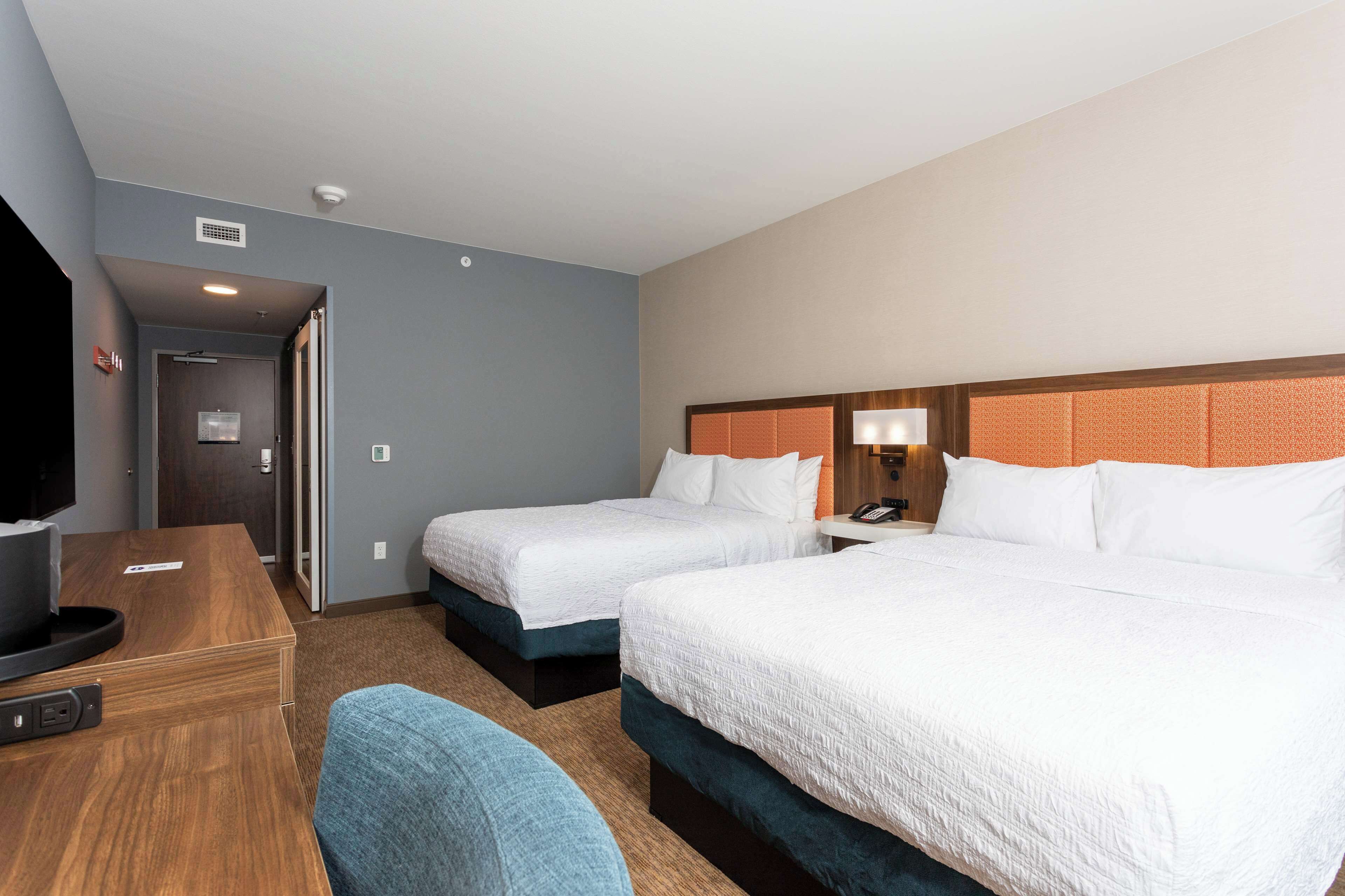A hotel room with two beds, a desk with a computer, and a TV.