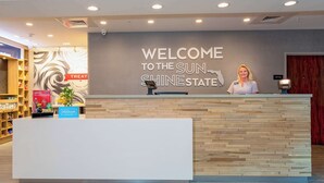 A hotel reception desk with a "Welcome to the Sun Shine State" sign, a "Hilton Hunger" sign, and a "Treat" sign. - Hampton Inn Marianna I-10 (Marianna)