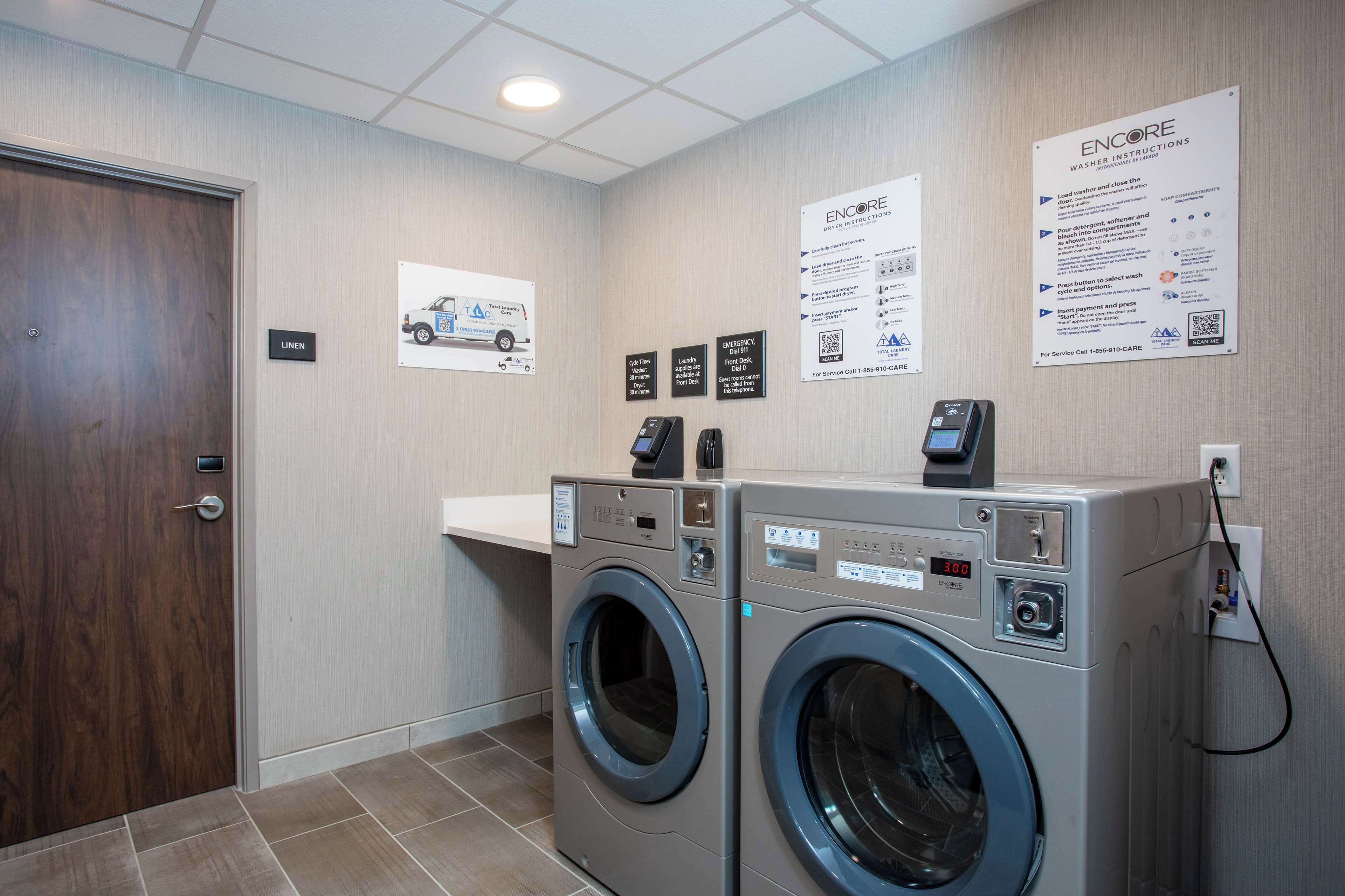 A laundry room with two front-loading washing machines, a sink, and a wooden door.
