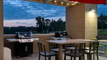 An outdoor patio with a grill, table, and chairs.