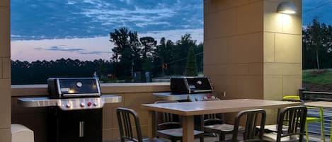 An outdoor patio with a grill, table, and chairs.