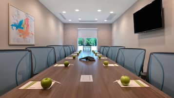 A conference room with a long table, chairs, a projector screen, and a map on the wall.