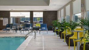 Un área de piscina con sillones de descanso y plantas en macetas.