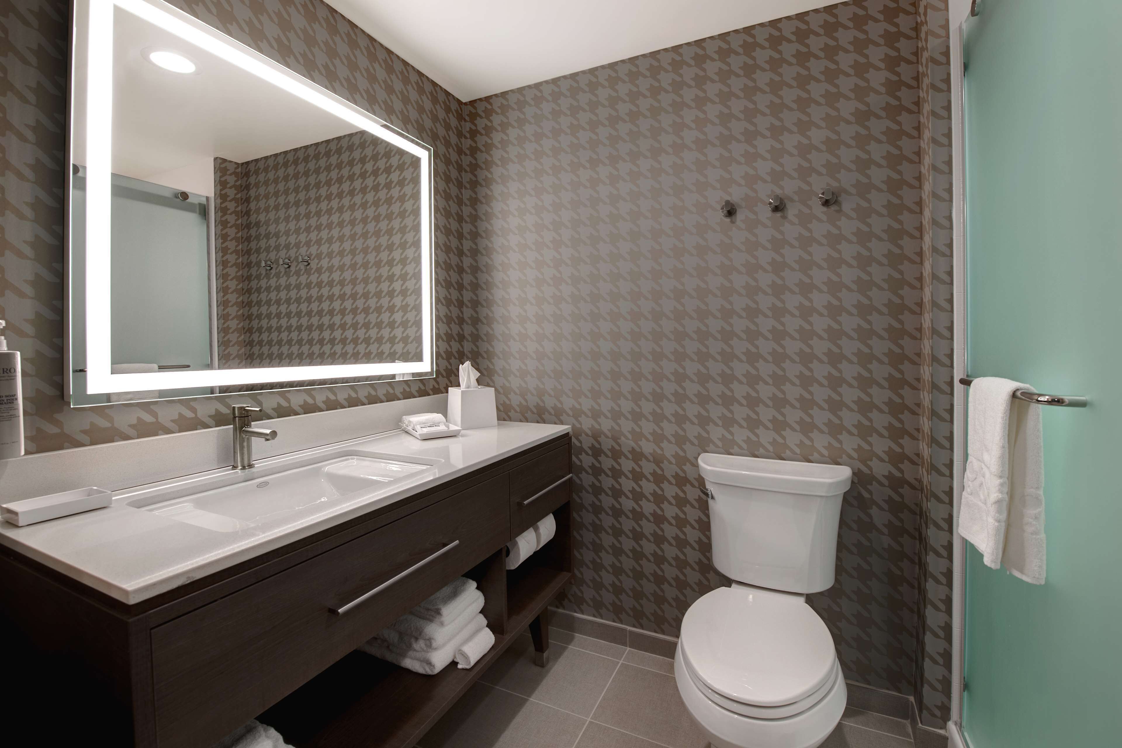 Un baño moderno con un espejo grande, lavamanos dobles, inodoro y zona de ducha.