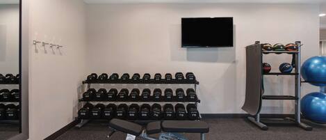 Une salle de sport équipée de matériel de musculation, de ballons d’exercice et d’un banc.
