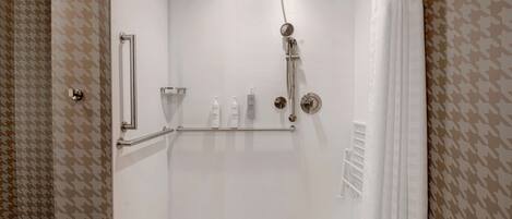 Eine begehbare Dusche mit Glastür, Handlauf und Duschkopf.