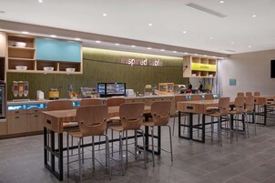 A restaurant with a counter, multiple tables, and chairs.