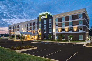 A modern hotel with a flat roof, multiple floors, and a parking lot.