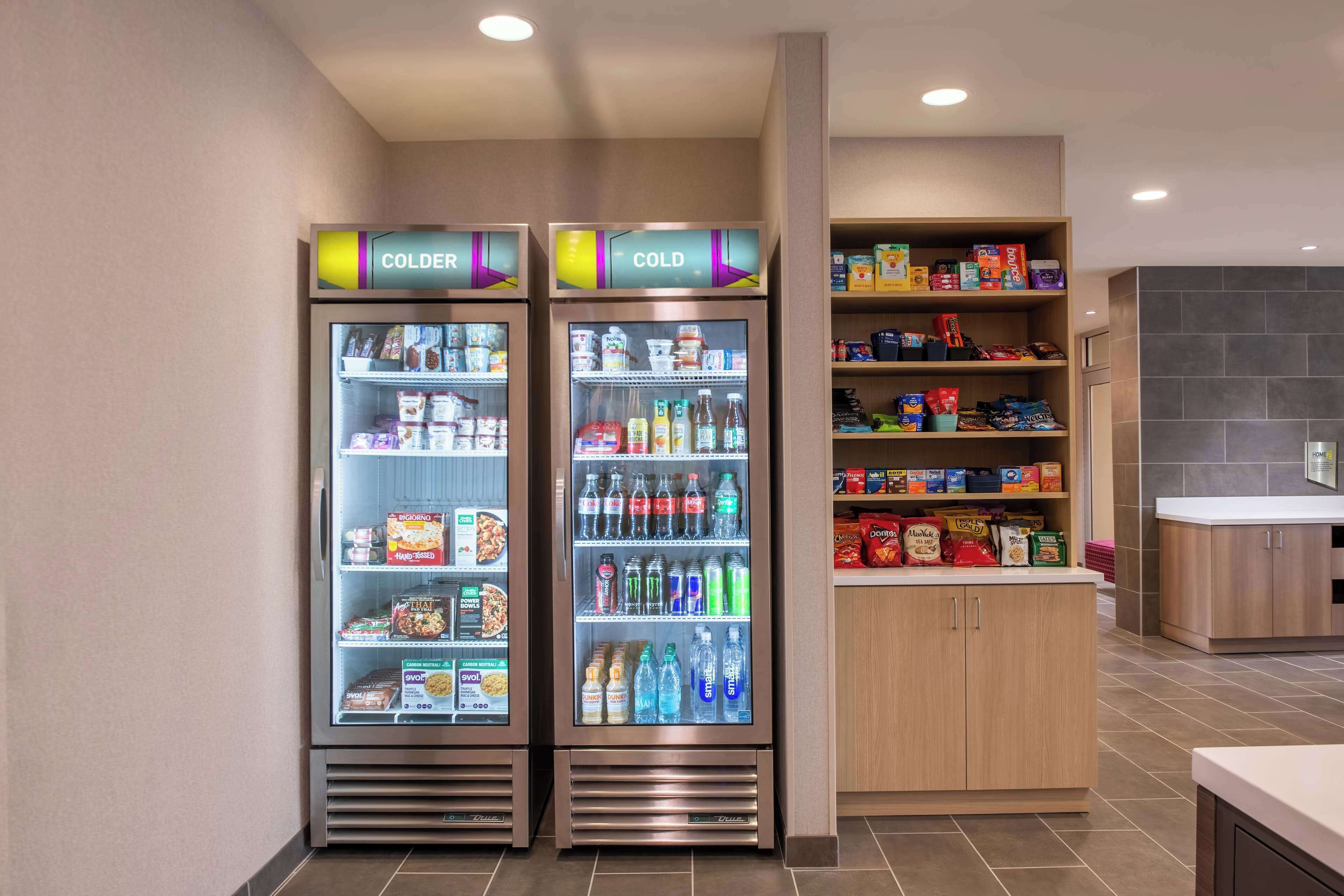Eine Hotelküche mit zwei gekühlten Vitrinen, beschriftet mit „COLDER“ und „COLD“, voll mit Getränken und Snacks.