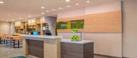A hotel reception area with a counter, a desk, and a seating area with chairs.