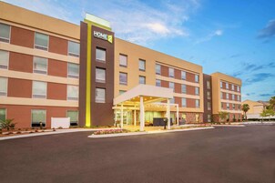 Un hotel moderno con entrada cubierta, varios pisos y cielo despejado.