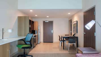A modern hotel room with a desk, office chair, dining table, and chairs.