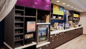 A modern breakfast bar with a refrigerator, juice dispenser, and various food items.