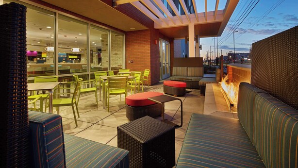 An outdoor seating area with wicker furniture, a fire feature, and a view of the cityscape.