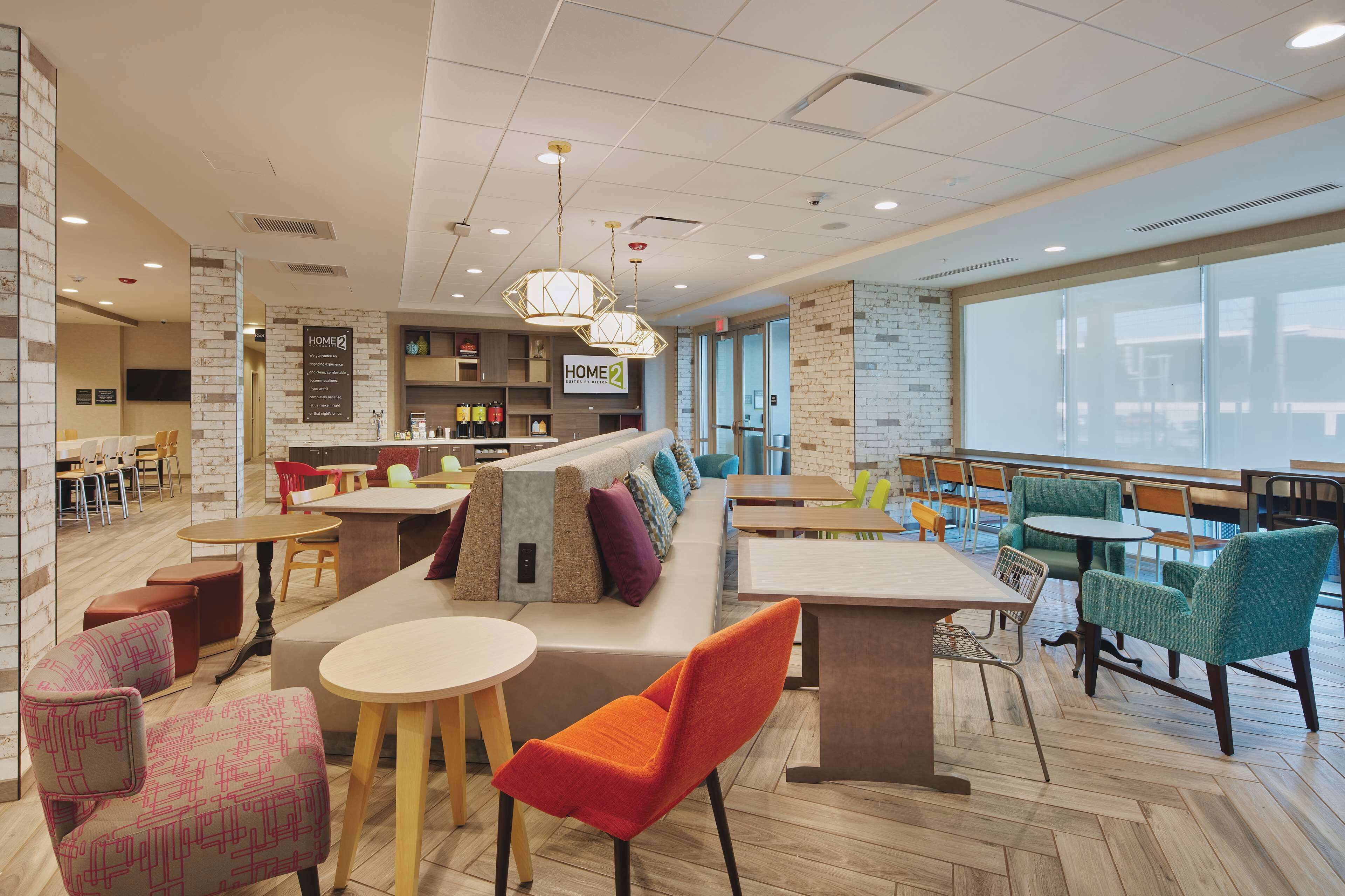 A modern lounge area with seating arrangements, a bar area, and a large window providing natural light.
