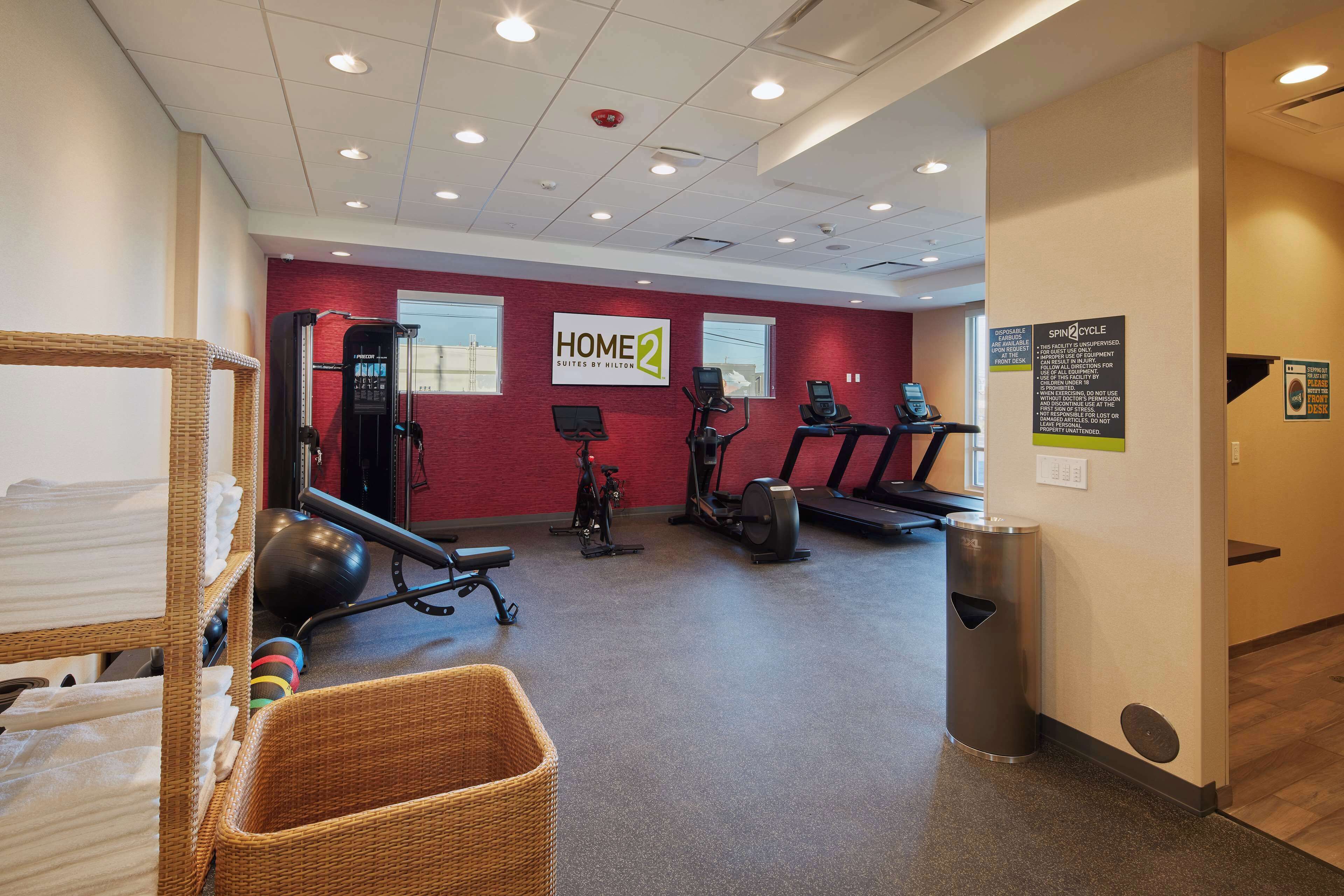 A fitness center with treadmills, elliptical machines, and a wall-mounted TV.