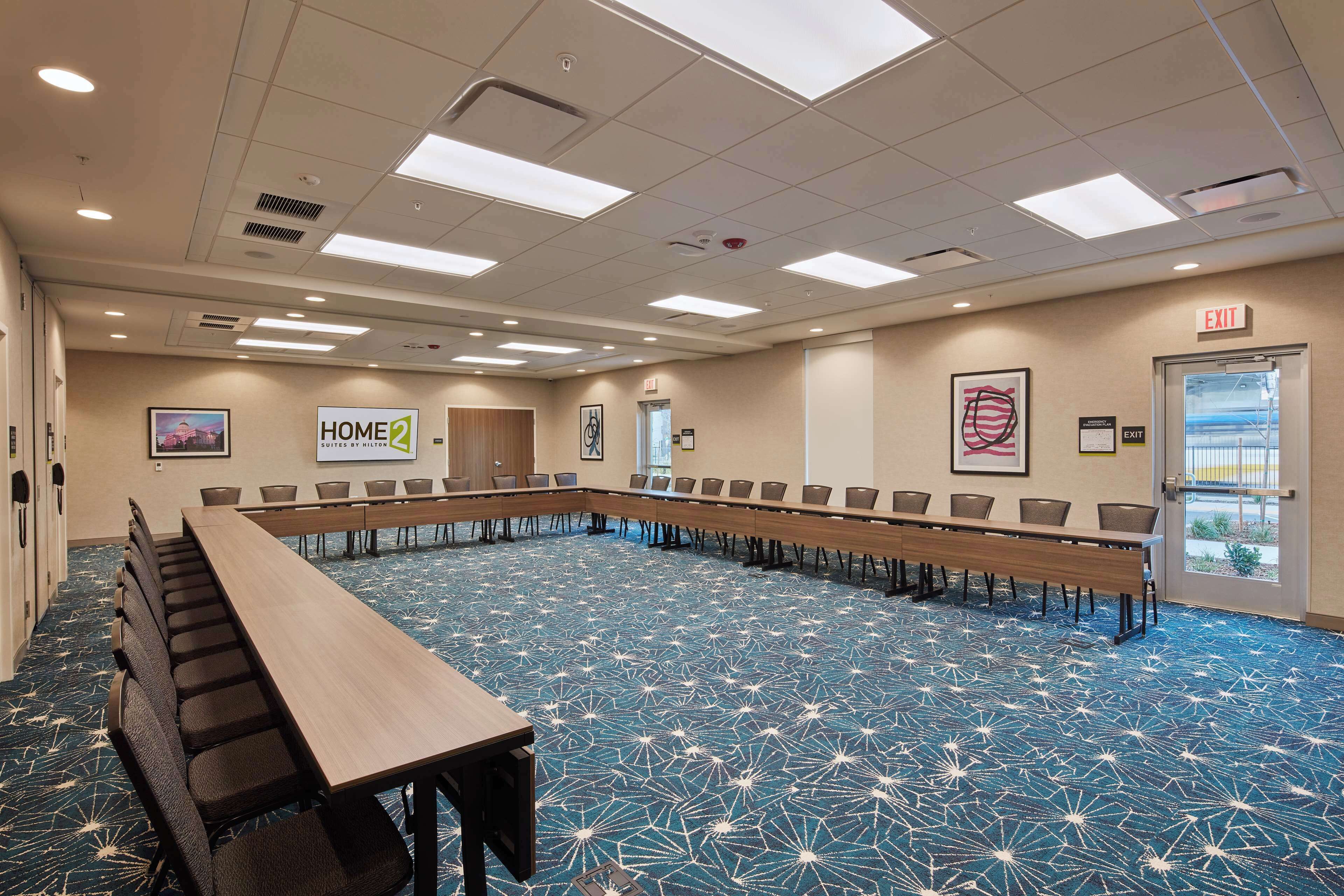 Una sala de conferencias con una larga mesa, sillas y una alfombra azul estampada.
