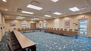 Una sala de conferencias con una larga mesa, sillas y una alfombra azul estampada.