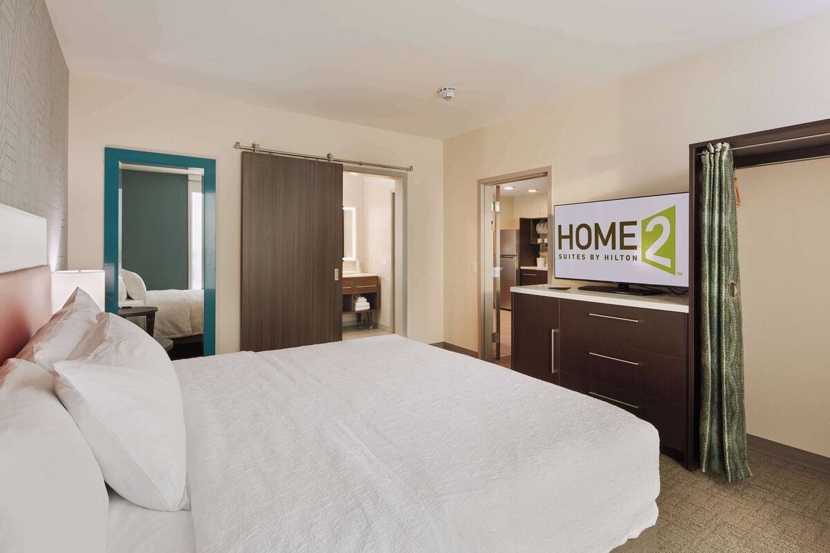 Een hotelkamer met een bed, televisie, badkamer en kitchenette.