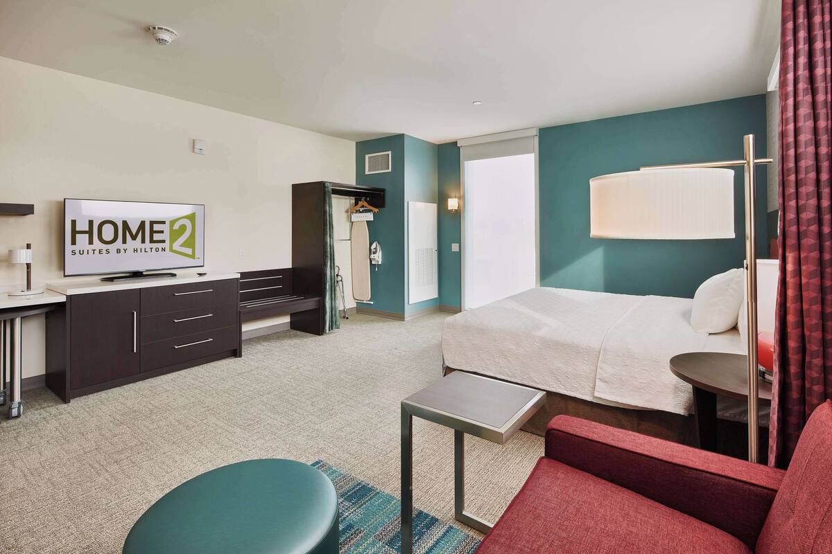 Een hotelkamer met een bed, een televisie, een bureau en een zithoek.