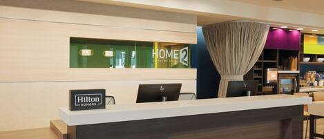 A hotel reception desk with a sign for 'Hilton Honors' and 'Home 2 Suites by Hilton'.