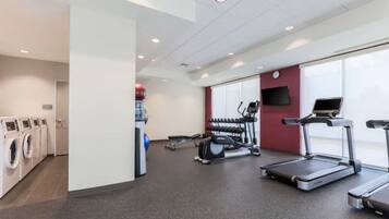 A gym with stationary bikes, treadmills, and a washing machine area.