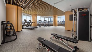 Une salle de sport équipée de tapis de course, de vélos elliptiques et de bancs de musculation.