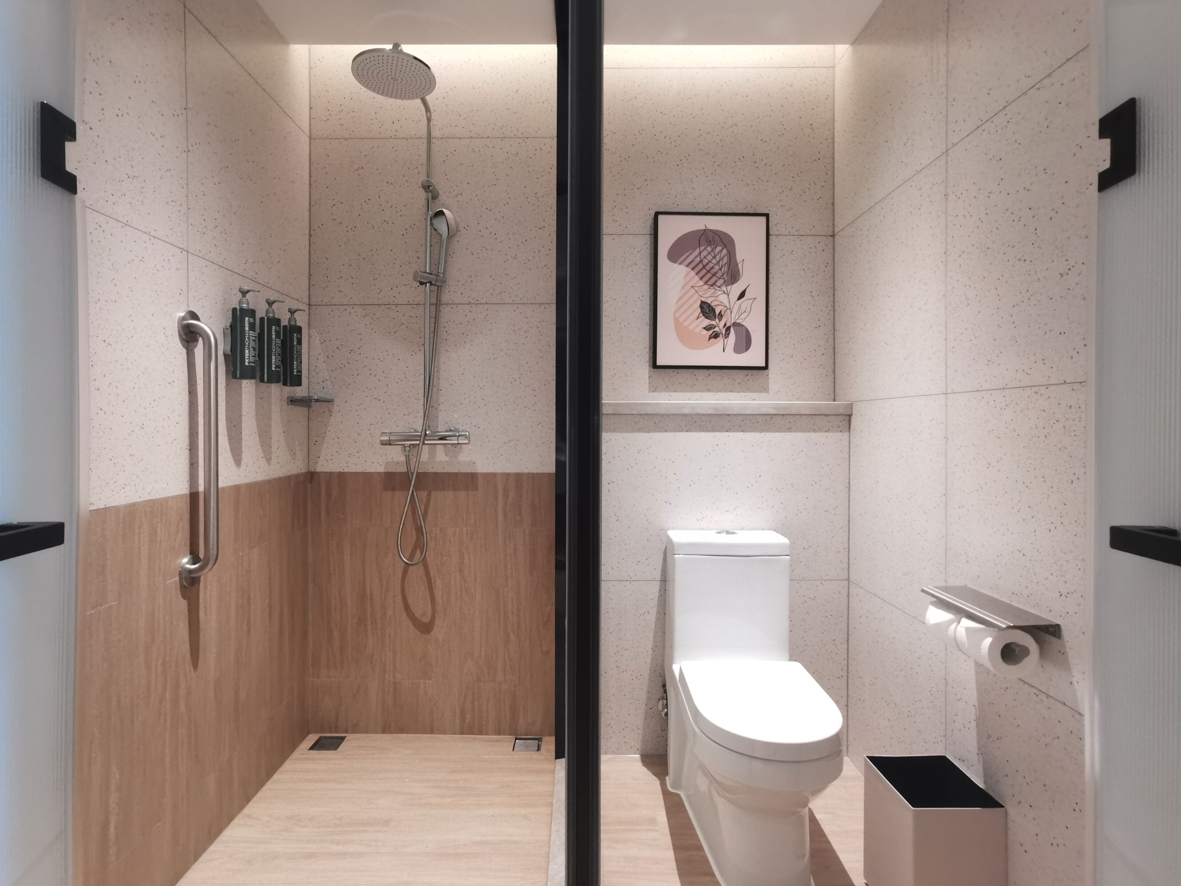 Un baño moderno con ducha, inodoro y barras de apoyo.