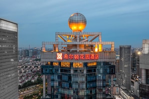 A hotel with a distinctive spherical structure on top, surrounded by modern buildings.