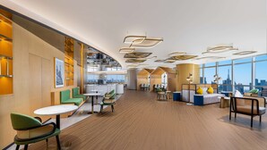 Un intérieur moderne comprenant des coins salon, une cuisine et de grandes fenêtres donnant sur la ville.