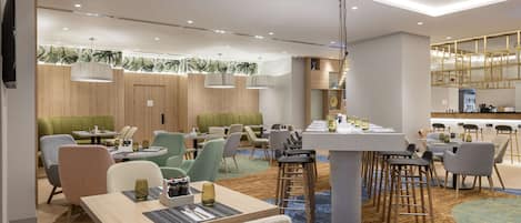 Un restaurante moderno con varias zonas de estar, incluyendo cabinas y mesas, además de una barra.