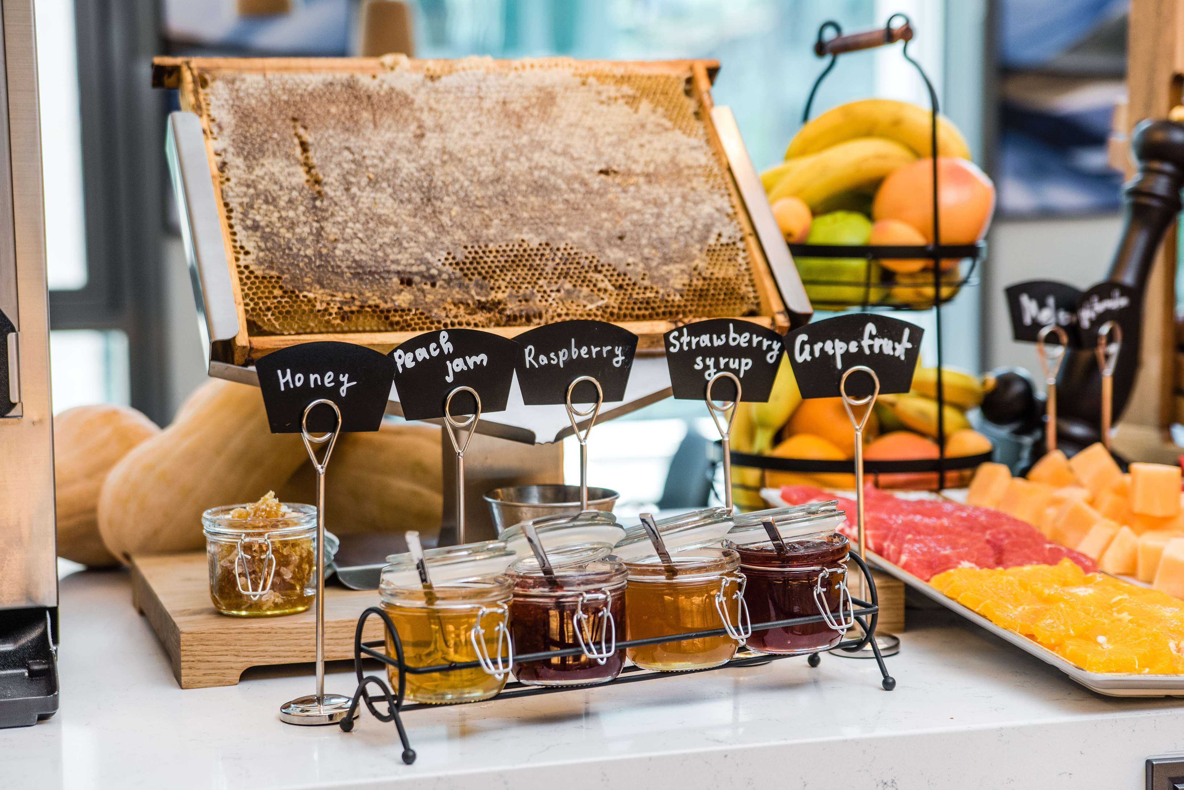 A honey stand with jars labeled honey, peach jam, raspberry, strawberry syrup, and grapefruit.