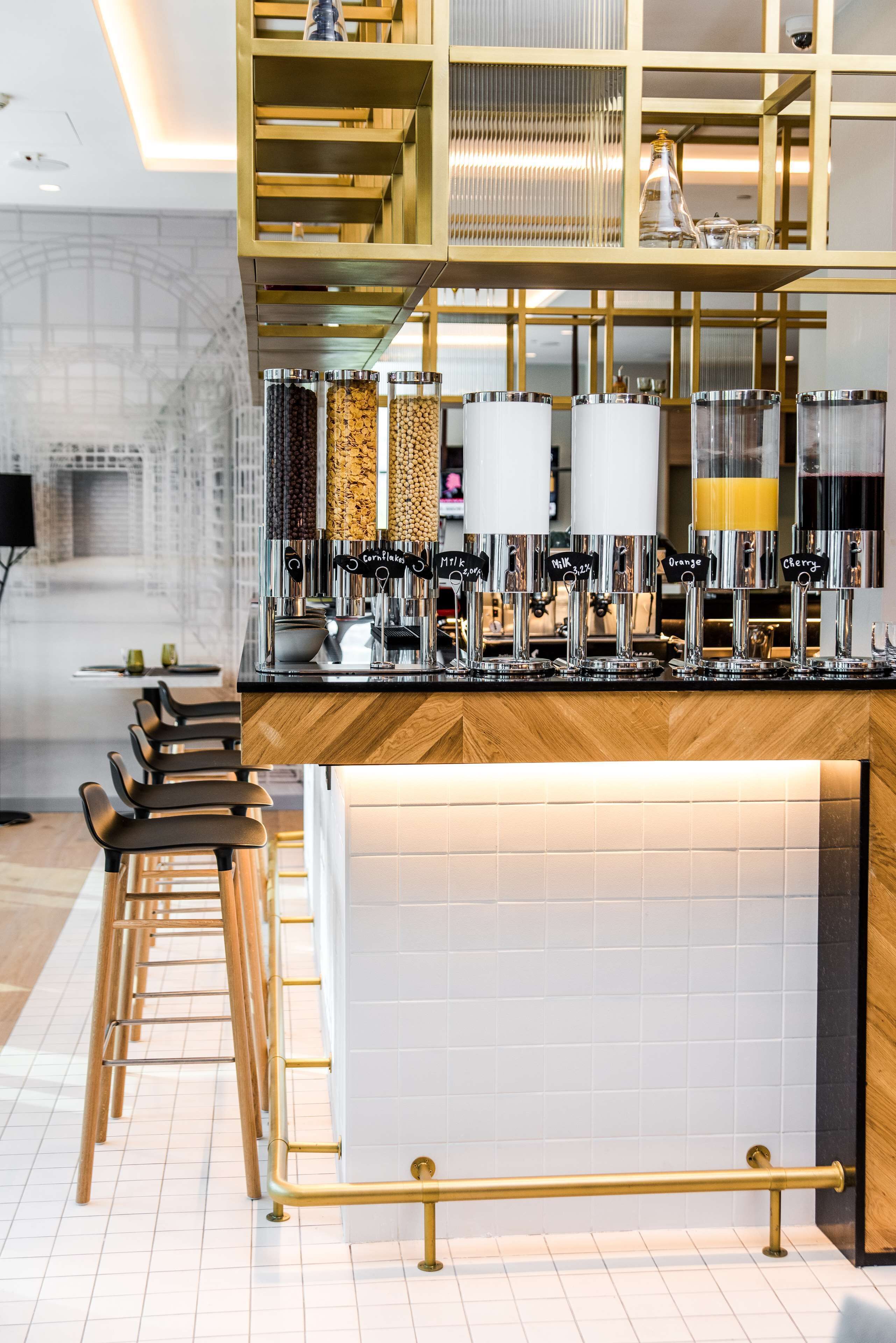 A modern bar area with a coffee machine, seating, and a decorative shelf.
