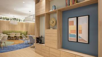 A modern interior with a green sofa, white chairs, a blue rug, and wooden shelves with books and decorative items.