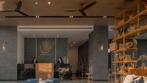 Eine moderne Lobby mit einer Rezeption, blauen Sitzgelegenheiten und einer Holzauslage mit Taschen.
