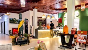 A lobby with a reception desk, a statue, and a seating area with a glass table.
