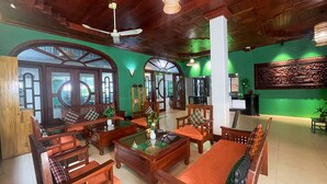 A spacious room with wooden furniture, large windows, and a ceiling fan.