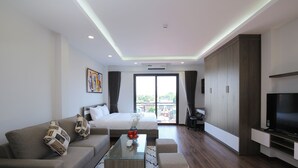 Habitación de hotel moderna con cama, sofá, televisión y balcón con vistas.