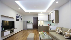 Una sala de estar moderna con un televisor de pantalla plana, una mesa de centro de vidrio y un sofá con cojines estampados.