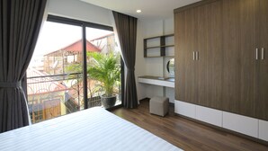 Un dormitorio moderno con un ventanal grande, una planta en maceta, una cama y un armario.