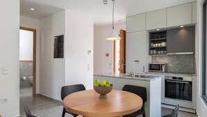 Une cuisine moderne équipée d’un four à micro-ondes, d’un four traditionnel et d’un saladier rempli de fruits, le tout placé sur l’îlot central.