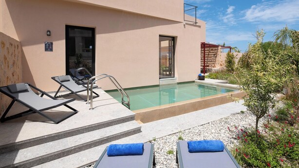 Un espace aménagé au bord de la piscine, avec des chaises longues, une piscine et la façade d’un bâtiment.
