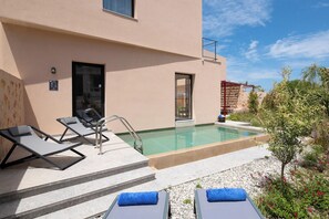 A poolside area with lounge chairs, a pool, and a building facade.